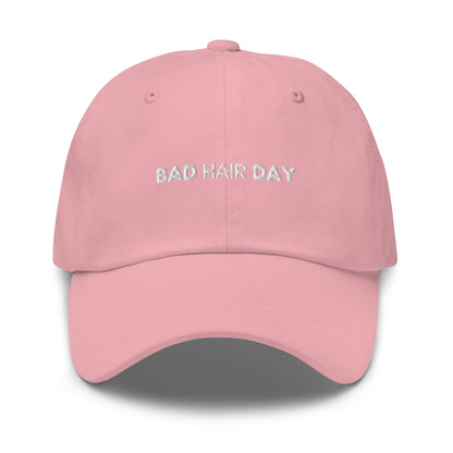 a pink hat with white sarcastic, bad hair day, text on it